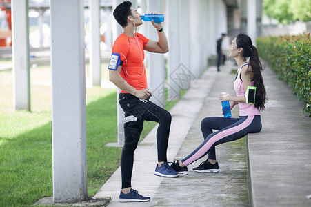 年轻男女在户外锻炼后休息喝水背景图片