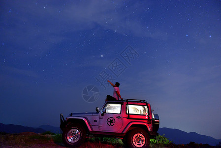 红色星光素材星空下车顶上的单人背景