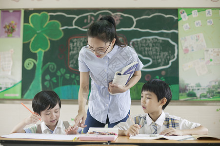 拿课本的女老师上课时老师在辅导学生认真学习背景