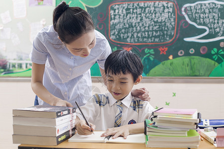 女老师在教室里给男同学辅导背景图片