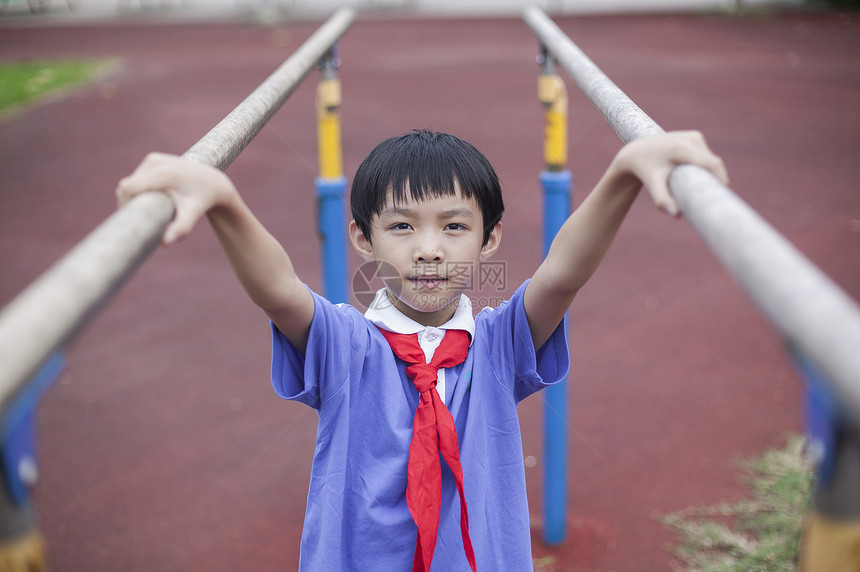 男同学在操场上锻炼双杠图片