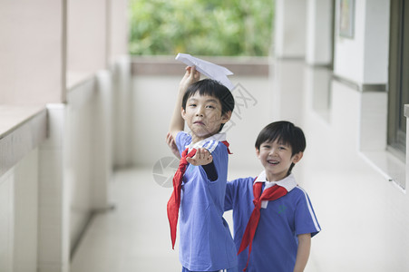 男学生在学校里折飞机玩耍背景图片