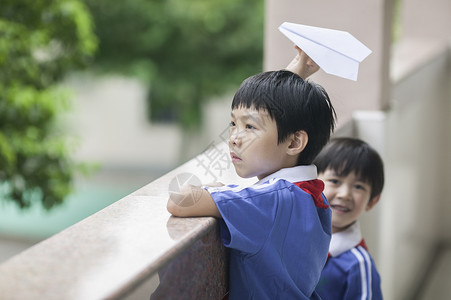 男学生在学校里折飞机玩耍背景图片