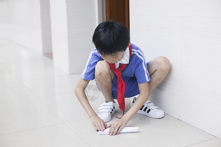 男学生在学校里折飞机玩耍背景图片