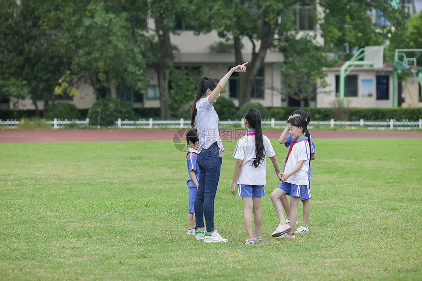 校园里女老师和同学们在草坪上一起玩耍图片