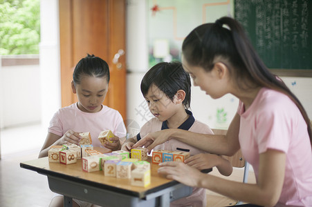 男女同学和女老师在教室里玩积木图片