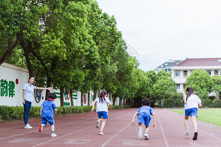 开心人民教师老师看孩子们在操场上奔跑背景