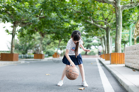 打篮球的女孩校园林荫道上打篮球的小学生女生背景