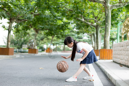 女孩打篮球校园林荫道上打篮球的小学生女生背景