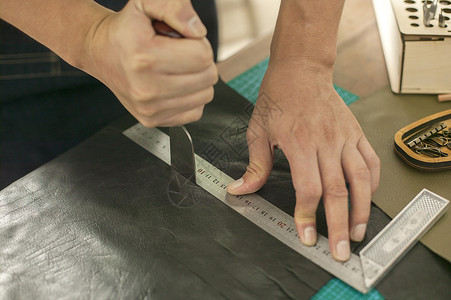 人物磨皮素材皮匠师傅专注的在裁切皮革背景