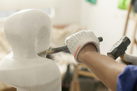 专注的石匠雕刻师傅在雕刻作品高清图片