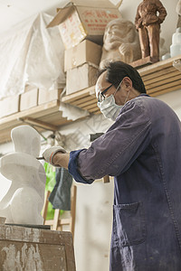 专注的石匠雕刻师傅在雕刻作品背景图片