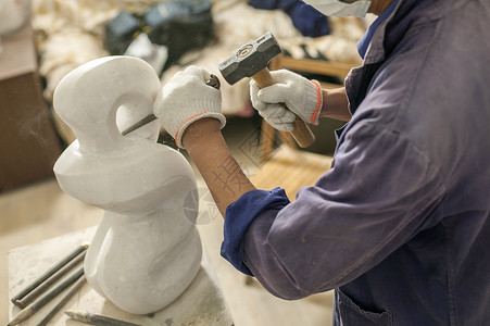 专注的石匠雕刻师傅在雕刻作品高清图片