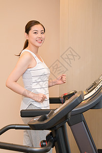 年轻女子在跑步机上运动跑步图片