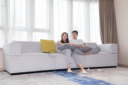 情侣在客厅沙发放松休闲看电视背景图片