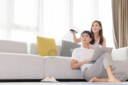 年轻夫妻一起在客厅沙发上看电视高清图片