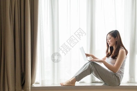 坐在窗台使用电脑休闲放松的女性高清图片