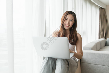 坐在窗台使用电脑休闲放松的女性高清图片