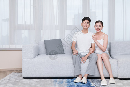 年轻夫妻坐在客厅沙发上背景图片
