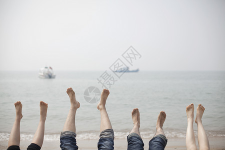 旅行中一家人在海边抬脚放松高清图片