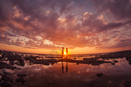 海滩日旅行中情侣在夕阳下浪漫对视背景