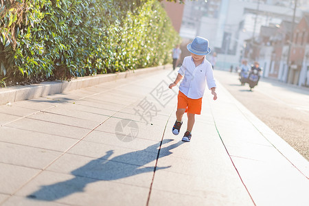 孩子帽子人行道上孩子阳光里的影子背景