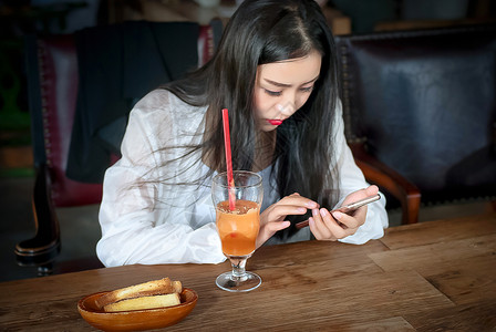 木桌子和咖啡厅玩手机的年轻女生背景