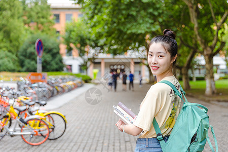 大学校园内女生抱着书本背景