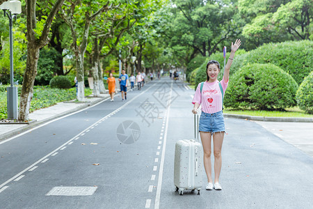 校园内女生拉旅行箱挥手背景图片