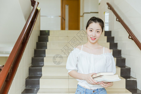 大学教学楼内女生抱着书本背景