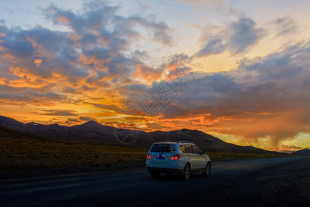 道路崎岖夕阳下行驶在公路上的汽车背景