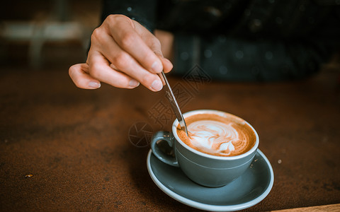 手拿勺子搅动咖啡高清图片