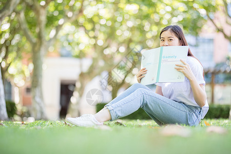 坐在校园草坪上看书的女学生图片