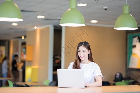 咖啡馆女性办公看电脑使用的电脑的年轻女性背景