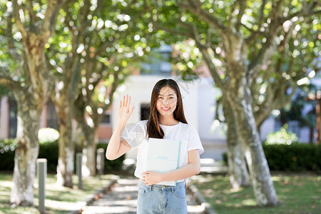 校园里拿着书微笑打招呼的女生图片