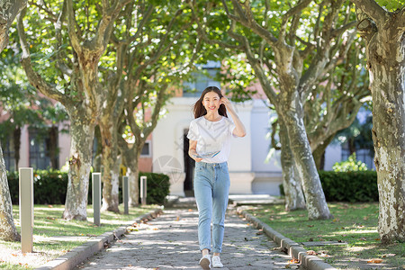 学校里抱着书边走路边撩头发的女同学背景图片