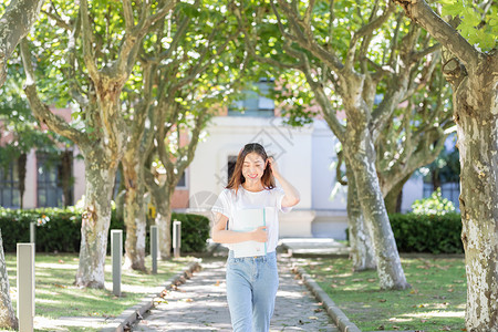 学校里抱着书边走路边撩头发的女同学背景图片