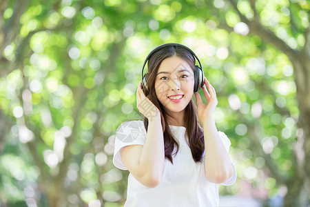 大学生笑脸头戴耳机听音乐的少女背景