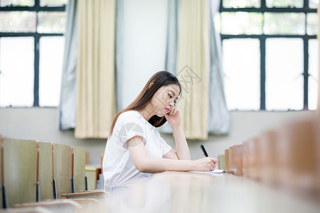 演讲女同学教室里正在学习写字的女生同学背景