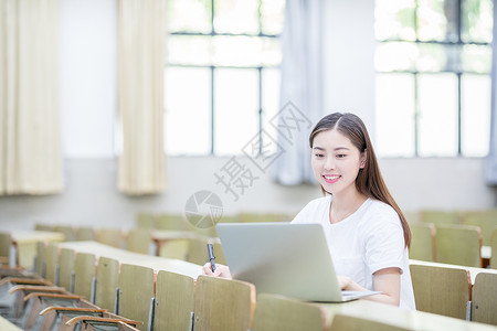 演讲女同学教室里使用笔记本电脑学习的学生背景