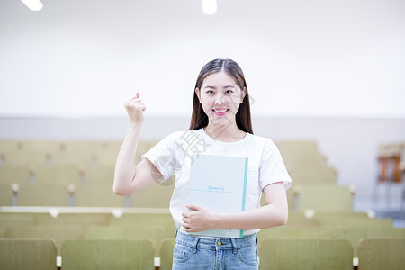 抱着书女同学抱着书自信的站在教室里的大学生背景