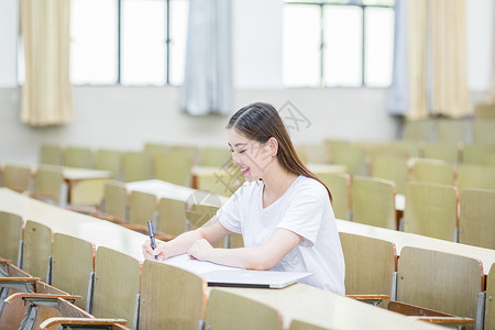 教室里自习学习写字的女大学生背景图片