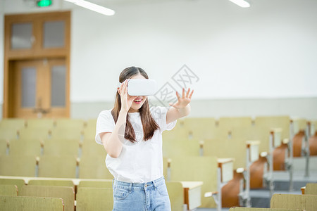 伸手女同学戴着VR眼镜伸手触摸前方背景