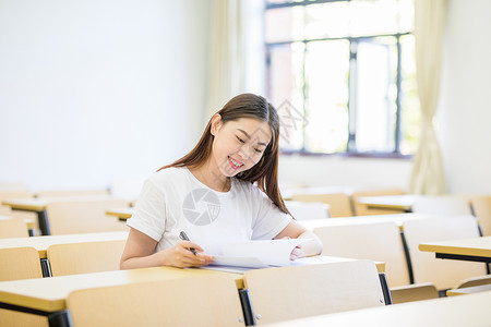 女同学演讲教室里自习学习写字的女大学生背景