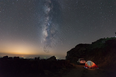 银河中最亮星银河下的帐篷和越野车背景