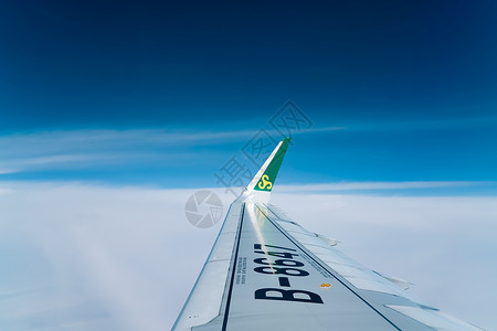 旅途中舷窗外蓝天中的机翼背景