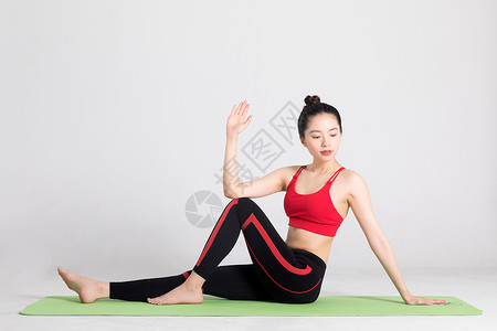 伸展式坐在瑜伽垫上做瑜伽动作的女性背景