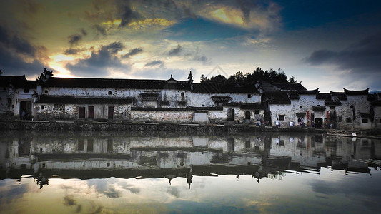 傍晚池塘边的徽派建筑水乡古镇背景图片