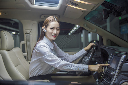 戴蓝牙耳机的商务女性开车背景图片