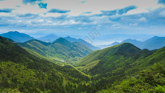 青山村蓝天白云下的绿色山脉背景